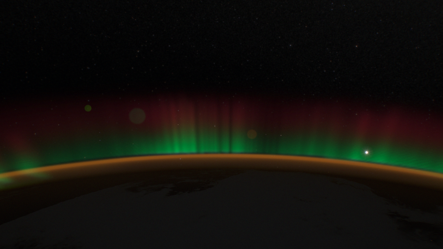 A smooth band of green with red haze above the horizon.