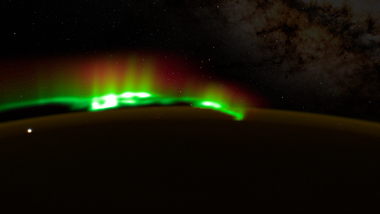 A thick soft aurora band with bright white clumps along its base.