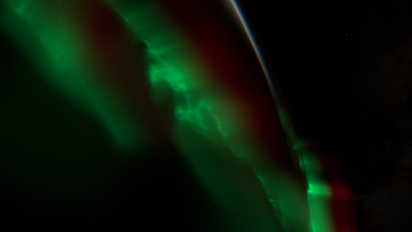 A close view of green curtains with a soft red upper layer along the limb.